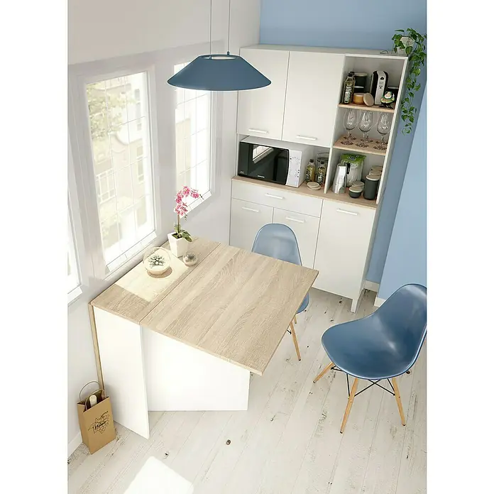 Mesa auxiliar Fly - L x An x Al: 31 x 77 x 78 cm, Blanco Artik/Roble Canadian, Abatible - Comedor luminoso con mesa de madera y sillas azules, iluminado por una lámpara azul. Moderna cocina americana al fondo.