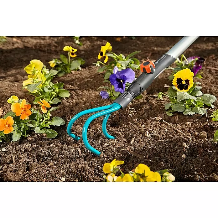 Gardena Combisystem Kleingeräte-Set - 4 -tlg. - Blauer Gartenkultivator mit grauem Griff im Boden zwischen bunten Stiefmütterchen.