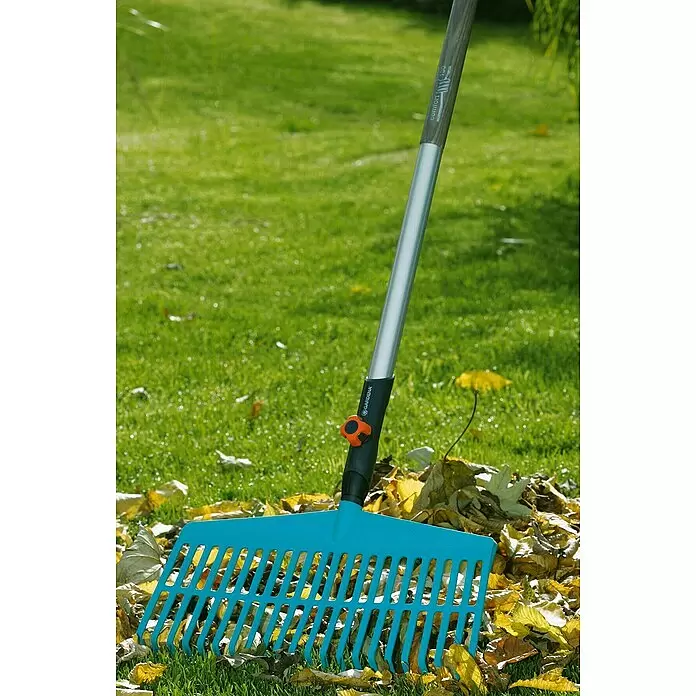Gardena Combisystem Kleingeräte-Set - 4 -tlg. - Blauer Kunststoff-Gartenrechen mit silbernem Stiel, der in einem Haufen gelber Herbstblätter steht.