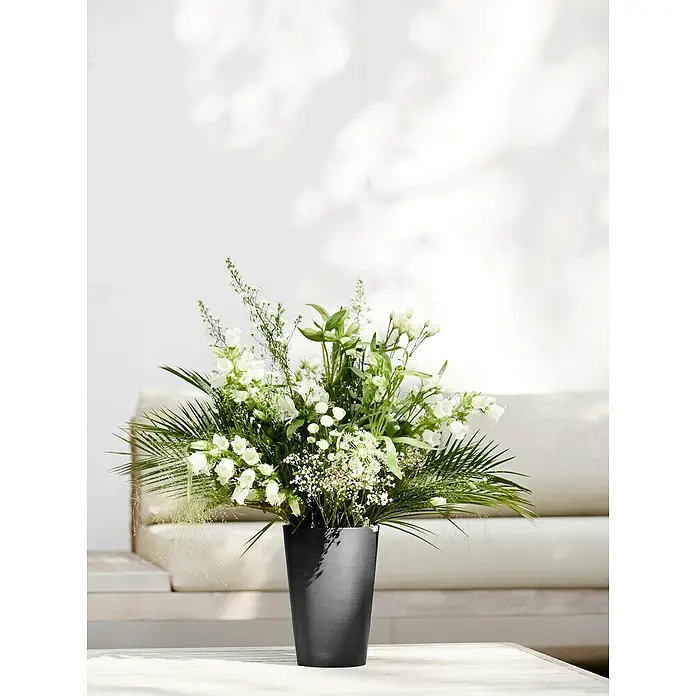 Ecopots Vase Pisa - Ø x H: 17,8 x 25,2 cm, Kunststoff, Dunkelgrau - Eine Nahaufnahme eines schwarzen Blumentopfes mit einem frischen Arrangement aus weißen Blüten und grünen Blättern.