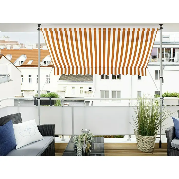 Sunfun Klemmmarkise - Orange/Weiß, Breite: 3 m, Ausfall: 1,5 m - Eine Markise mit orange-weißen Streifen spendet Schatten auf einem Balkon mit Möbeln und Pflanzen. Die Markise schützt vor Sonne.