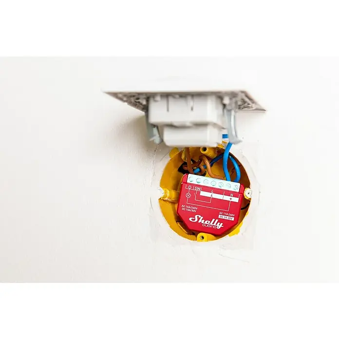 Shelly Relais-Modul Qubino Wave 1PM - Z-Wave Plus - Nahaufnahme eines Shelly Qubino Smart Home Geräts, das in einer gelben Verteilerdose installiert ist und mit blauen und braunen Kabeln verbunden ist.