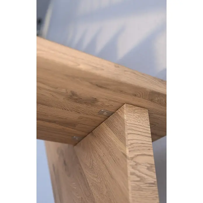 Starwood Raumspartreppe Lindos - Breite: 100 cm, Eiche, Geschosshöhe: 300 cm, 1/4-gewendelt rechts, Montageseite Geländer: Wahlweise links/rechts, Designgeländer Edelstahl, Ohne Setzstufen - Detailansicht eines Holzmöbelstücks mit Tischplatte und Bein, befestigt mit einer Metallhalterung, die die natürliche Holzmaserung hervorhebt.