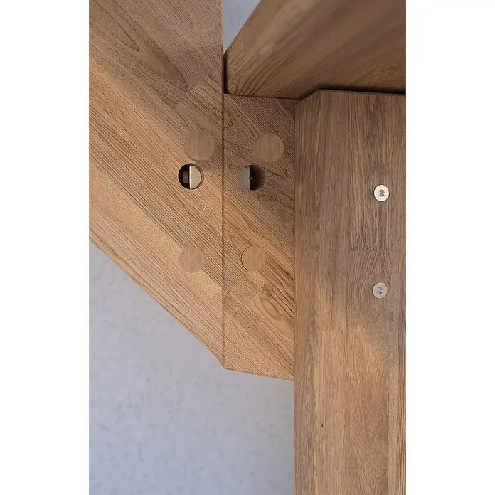 Starwood Raumspartreppe Lindos - Breite: 100 cm, Eiche, Geschosshöhe: 300 cm, 1/4-gewendelt rechts, Montageseite Geländer: Wahlweise links/rechts, Designgeländer Edelstahl, Ohne Setzstufen - Nahaufnahme eines Holzbalken-Verbindungsstücks mit sichtbaren Schrauben und Dübeln, die die Stabilität und Ästhetik der Konstruktion betonen.
