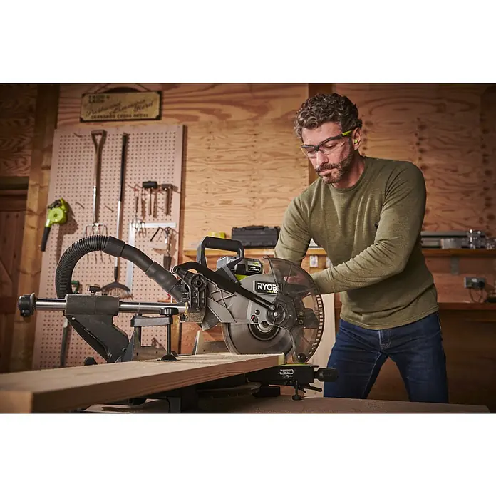 Ryobi ONE+HP Akku-Kapp- & Gehrungssäge RMS25418X-0 - 18 V, Ohne Akku, 4.100 U/min - Ein Mann in Arbeitskleidung bedient eine Ryobi-Kapp- und Gehrungssäge in einer Werkstatt, um ein Holzbrett präzise zu schneiden.