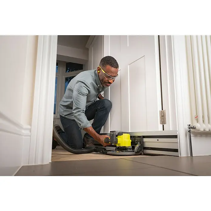 Ryobi ONE+HP Akku-Tauchsäge RPLS18X-0 - 18 V, Ohne Akku, Durchmesser Sägeblatt: 165 mm, Leerlaufdrehzahl: 4.300 U/min - Ein Mann kniet und arbeitet mit einer Ryobi-Elektrosäge, um einen Türrahmen zuzuschneiden, wobei er Schutzbrille trägt.