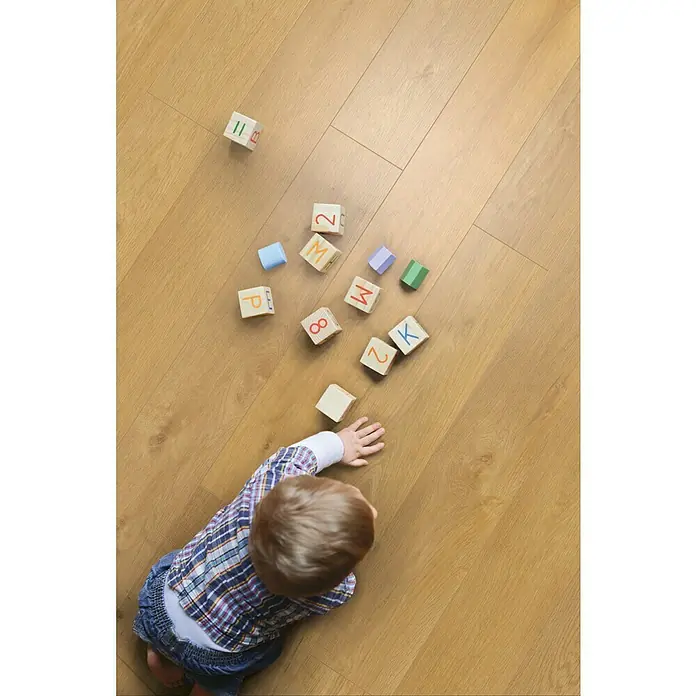 Krono Original Vinylbodenmuster Rocko Classic Crescendo - 297 x 192 x 5 mm, Landhausdiele, Crescendo - Ein Kind spielt mit bunten Bauklötzen auf einem hellen Holzboden, die Buchstaben und Zahlen zeigen.