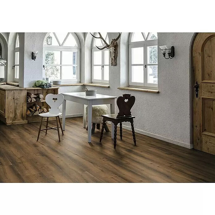 Krono Original Laminat Organic Veneer Parquet - Oak Roast, Landhausdiele, 1.383 x 244 x 8,5 mm - Dunkelbrauner Dielenboden in einem rustikalen Essbereich mit Tisch und Stühlen.