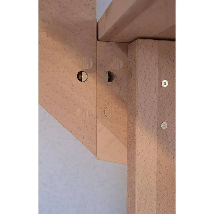 Starwood Raumspartreppe LindosBreite: 100 cm, Buche, Geschosshöhe: 300 cm, 1/4-gewendelt rechts, Montageseite Geländer: Wahlweise links/rechts, Designgeländer Edelstahl, Ohne Setzstufen - Detailansicht einer Holzkonstruktion mit sichtbaren Verbindungsstücken, die die hochwertige Verarbeitung und Stabilität des Produkts betont.