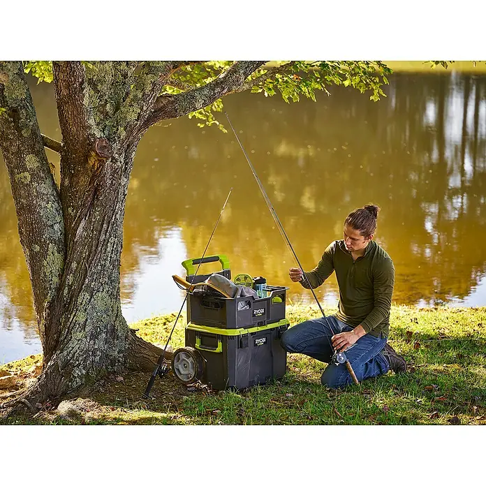 Ryobi Link Werkzeugkoffer RSL201 Trolley - L x B x H: 57 x 49,5 x 39 cm, Kunststoff, 2 Räder - Ein Angler bereitet seine Ausrüstung vor, mit einem RYOBI-Aufbewahrungssystem neben sich.