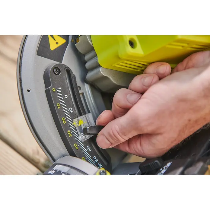 Ryobi ONE+HP Akku-Tauchsäge RPLS18X-0 - 18 V, Ohne Akku, Durchmesser Sägeblatt: 165 mm, Leerlaufdrehzahl: 4.300 U/min - Eine Nahaufnahme einer Ryobi-Kappsäge, bei der eine Hand den Winkel am Messgerät einstellt. Gut für Heimwerker- und Werkzeugprojekte.