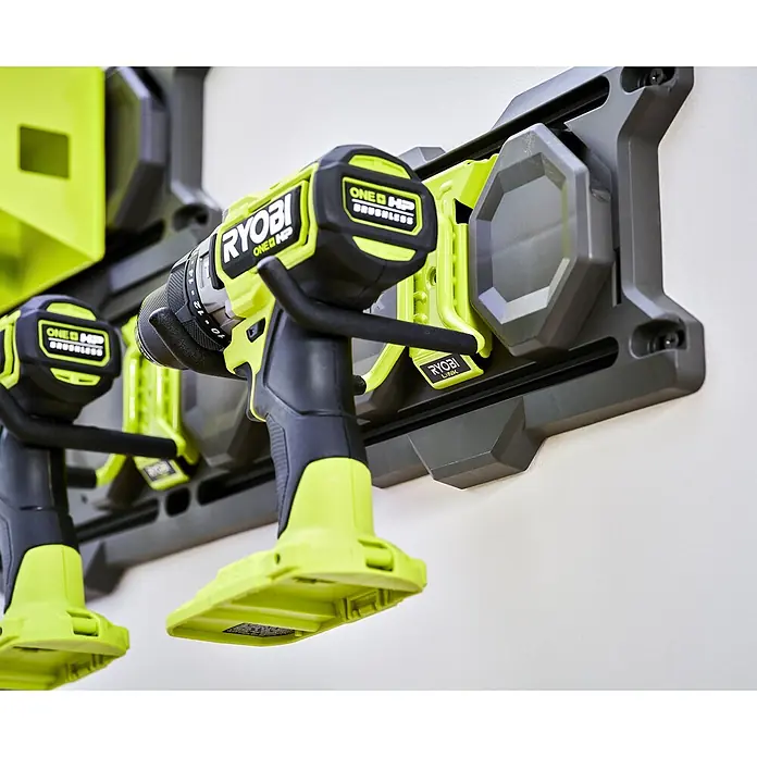 Ryobi Link Wandhalterung RSLW801 - Geeignet für: Handwerkzeuge, Größe: S, Passend für: Ryobi ONE+ Sortiment - Zwei Ryobi ONE+ HP Brushless Bohrmaschinen hängen an einer grauen Wandhalterung mit grünen Akzenten.