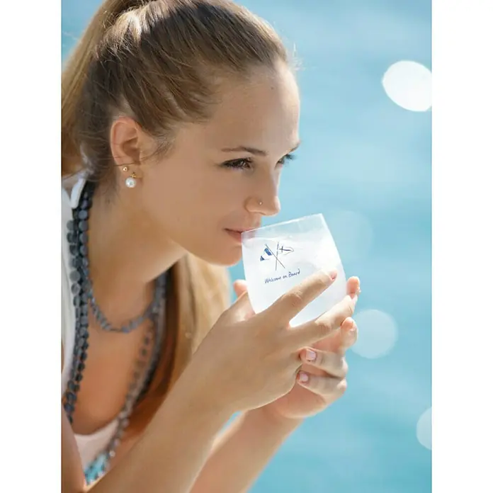Marine Business Welcome on Board Vaso para beber agua - 6 ud., Plástico, Transparente - Primer plano de una mujer bebiendo de una taza blanca con la inscripción 'Welcome on Board', sobre un fondo azul.