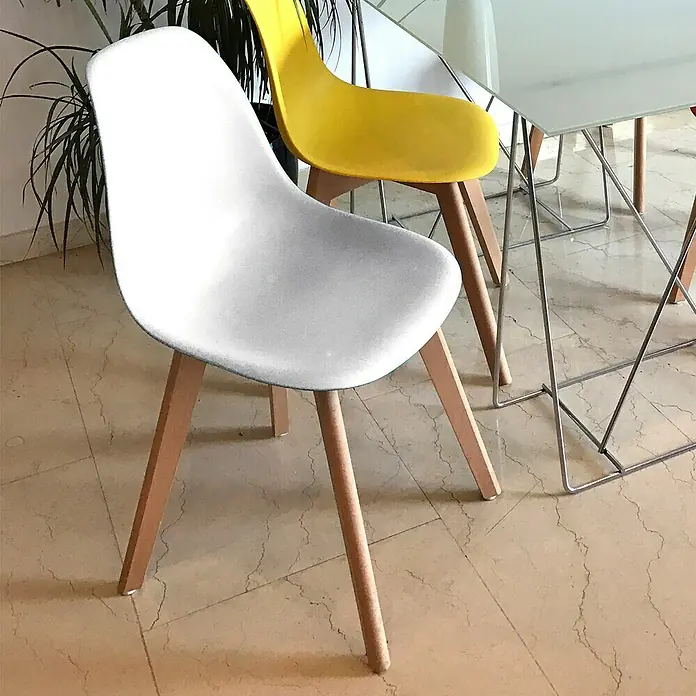 Home Deco Factory Silla Stockholm - Blanco, 4 pzs. - Toma luminosa de sillas elegantes con patas de madera, con una silla blanca en primer plano y una amarilla al fondo.