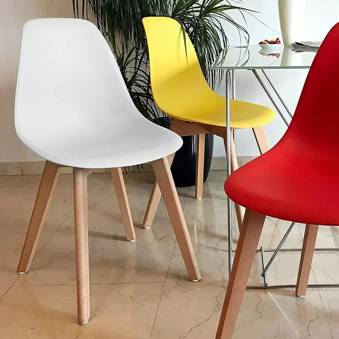 Home Deco Factory Silla Stockholm - Blanco, 4 pzs. - Primer plano de tres sillas modernas en blanco, amarillo y rojo con patas de madera clara, creando un comedor elegante.