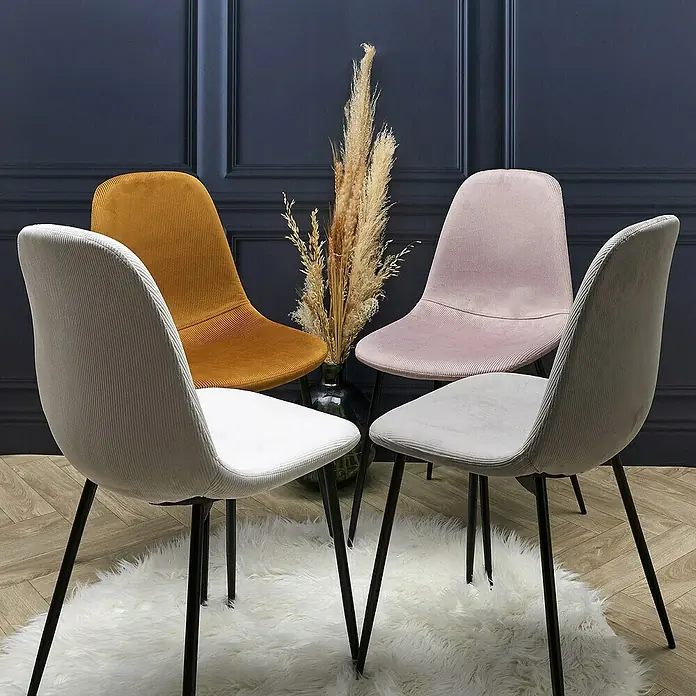 Home Deco Factory Silla Giulia - Gris claro, 4 pzs. - Toma de cuatro sillas de pana en varios colores dispuestas alrededor de un jarrón de flores sobre una alfombra de piel.