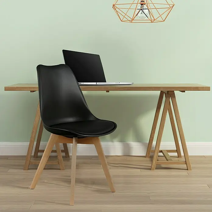 Silla Copenhague - Negro, 4 pzs. - Un escritorio moderno con una silla negra y un portátil encima, bajo una lámpara colgante geométrica, ofreciendo una solución de espacio de trabajo elegante.