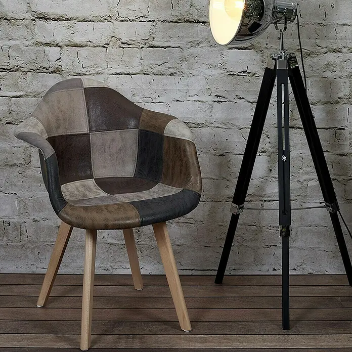 Home Deco Factory Silla butaca Patchwork - Marrón, 2 pzs. - Una colorida silla de cuero patchwork está al lado de una lámpara de pie frente a una pared de ladrillo. La silla tiene patas de madera clara.