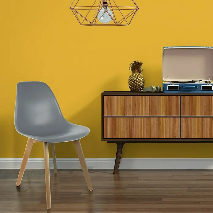 Home Deco Factory Silla Stockholm - Gris, 4 pzs. - Silla gris con patas de madera frente a una pared amarilla y cómoda con tocadiscos.