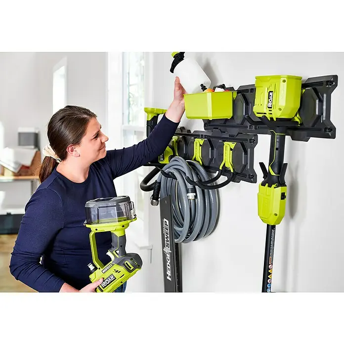 Ryobi Link Systemhalter RSLWPK-7PC - Geeignet für: Elektrowerkzeuge, 7 -tlg. - Eine Frau ordnet in einer Garage oder Werkstatt ihre RYOBI-Werkzeuge und -Zubehör an einer Wandhalterung. Praktische Aufbewahrung!