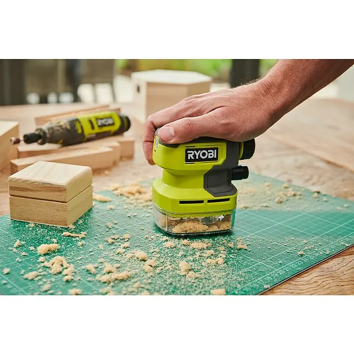 Ryobi 4V USB Akku-Staubsauger Mini RDV4-0 - 4 V, Ohne Akku, 70 ml - Nahaufnahme eines Ryobi-Elektroschleifers auf einer Werkbank, der Späne erzeugt.