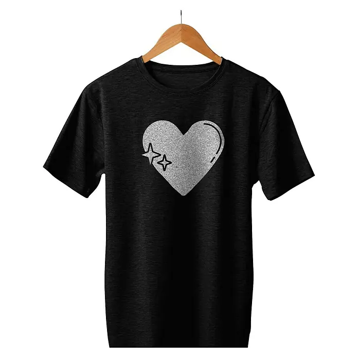 Cricut Joy Xtra Aufbügelfolie Smart Iron-On Prismatic Glitter - Silber, 1 Stk., L x B: 48,3 x 24,1 cm - Schwarzes T-Shirt mit Herz und Sternen-Motiv am Kragen, aufgehängt an einem Holzbügel. Das Shirt ist lässig und modisch.