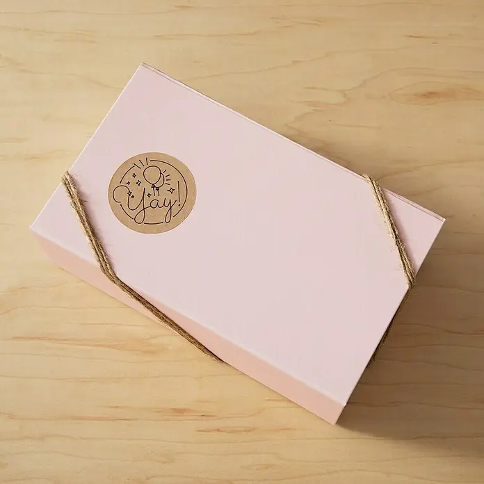 Cricut Joy Xtra Aufkleber Smart Label Paper Permanent - 4 Stk., Braun, 24,1 x 30,5 cm - Nahaufnahme einer rosa Geschenkbox, die mit einem Juteband und einem "Yay!"-Aufkleber verziert ist, für Geburtstage und besondere Anlässe.