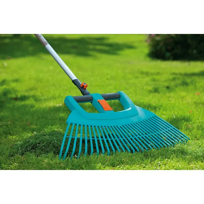 Gardena Combisystem Laubbesen XXL Vario - Ohne Stiel - Ein blauer Rechen mit verstellbaren Zinken liegt auf einem grünen Rasen. Das Gartengerät hilft beim Laubsammeln.