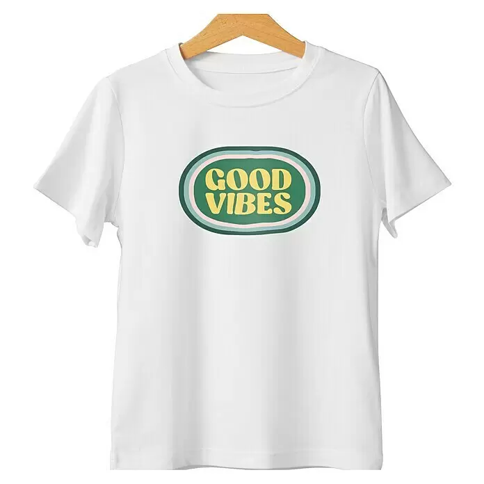 Cricut Aufbügelfolie Light Fabrics - 5 Stk., Weiß, L x B: 29,7 x 21 cm - Weißes T-Shirt mit „GOOD VIBES“-Grafik in einem grünen Oval, hängt an einem Holzbügel.