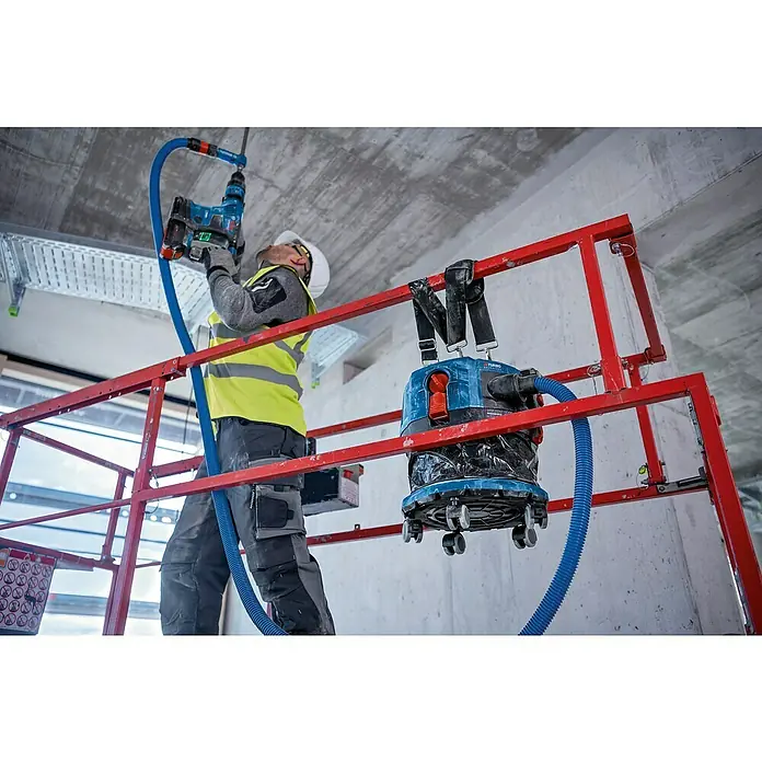 Bosch Professional AMPShare 18V Akku-Nass-Trockensauger GAS 18V-12 MC - Ohne Akku, 18 V, Behältervolumen: 12 l - Bauarbeiter bohrt mit Bosch Bohrhammer in Decke, Staub wird durch Sauger abgesaugt.