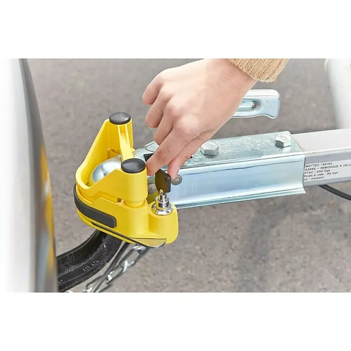 Mottez Dispositivo antirrobo A075B - L x An x Al: 20 x 9,5 x 10 cm - Candado amarillo MOTTEZ asegura el enganche del remolque mientras una mano acciona la llave.