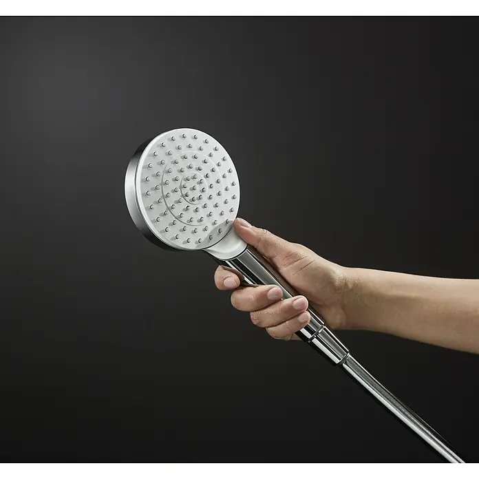 Hansgrohe Crometta Conjunto de ducha - Número de tipos de chorro: 1 ud., Cromo - Ducha de mano cromada con cabezal redondo y múltiples boquillas, sostenida por una mano frente a un fondo oscuro.