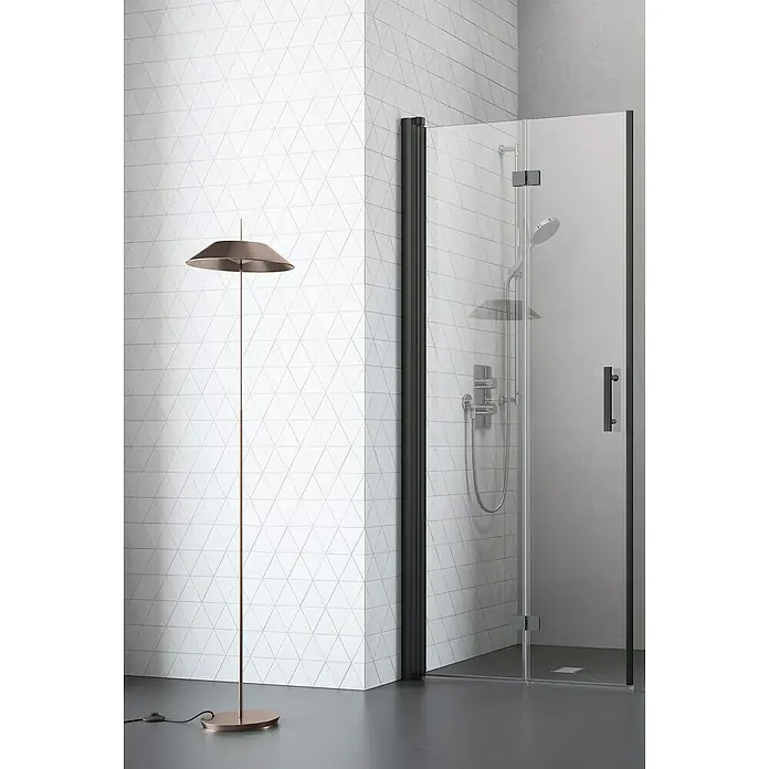 Camargue Vario Dusch-Falttür B52 - 80 x 195 cm, Beschichtet, Schwarz, Glasstärke: 6 mm - Elegante Duschkabine mit schwarzem Rahmen und einer modernen Stehlampe in einem Badezimmer mit dreieckigen Fliesen.