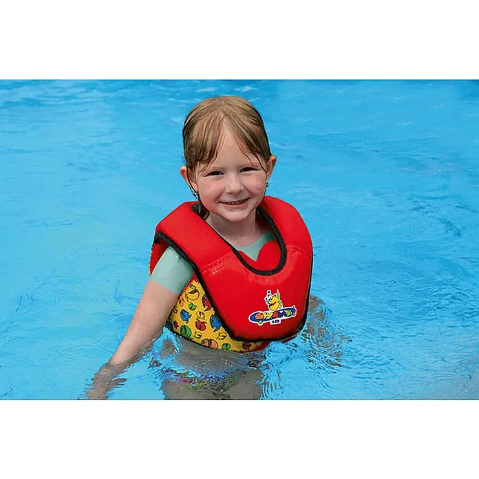 Grabner Schwimmhilfe Swimy Kid Mini - Buntes Kinderdesign, 10 kg - 20 kg - Ein lächelndes Mädchen im Schwimmbad mit einer roten Schwimmweste, die mit bunten Motiven verziert ist.
