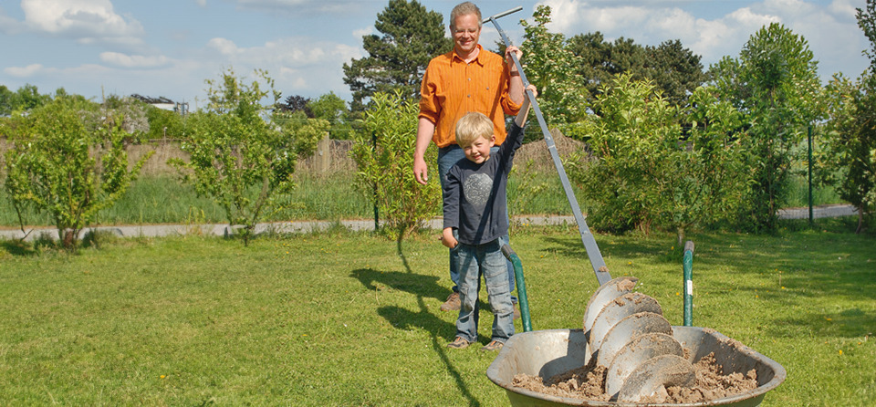Mann und Kind halten Erdbohrer fürs Brunnen selber bohren