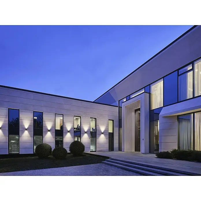 Ledvance Akku-Wandleuchte Endura Style Adjustable Beam Sensor USB - 10 x 9,7 x 12,6 cm, Grau, Warmweiß, 2,5 W, IP54 - Fassade eines modernen Gebäudes mit großen Fenstern und Beleuchtung, die eine stilvolle und einladende Atmosphäre schafft.
