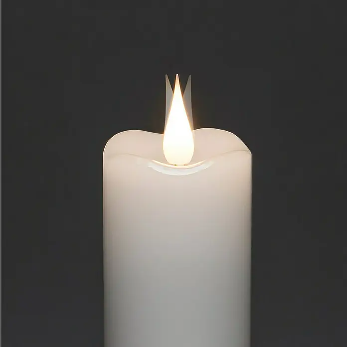Konstsmide LED-Kerze - Weiß, Ø x H: 7,8 x 17 cm, Echtwachs - Nahaufnahme einer weißen LED-Kerze, die ein warmes, flackerndes Licht ausstrahlt, perfekt für stimmungsvolle Beleuchtung ohne Brandgefahr.