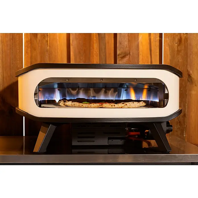 Cozze Pizzaofen mit drehbarem Pizzastein - Durchmesser Grillfläche: 42,5 cm, 6 kW, Weiß/Schwarz, Stahl - Pizzaofen mit einer köstlichen Pizza im Inneren, die auf einem Tisch mit Holzpaneelen im Hintergrund steht.