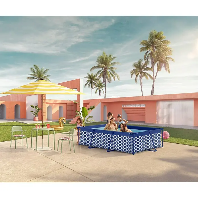 Swim Essentials Frame-Pool - L x B x H: 260 x 160 x 65 cm, Blau/Weiß, 2.163 l - Bild eines rechteckigen Aufstellpools im Garten, umgeben von Palmen und einem farbenfrohen Gebäude.