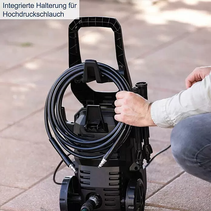 Scheppach Hochdruckreiniger HPC1600-Kit - 135 bar, 1.600 W, Fördermenge: 420 l/h - Mann wickelt den schwarzen Hochdruckschlauch auf die integrierte Halterung eines schwarzen Hochdruckreinigers.
