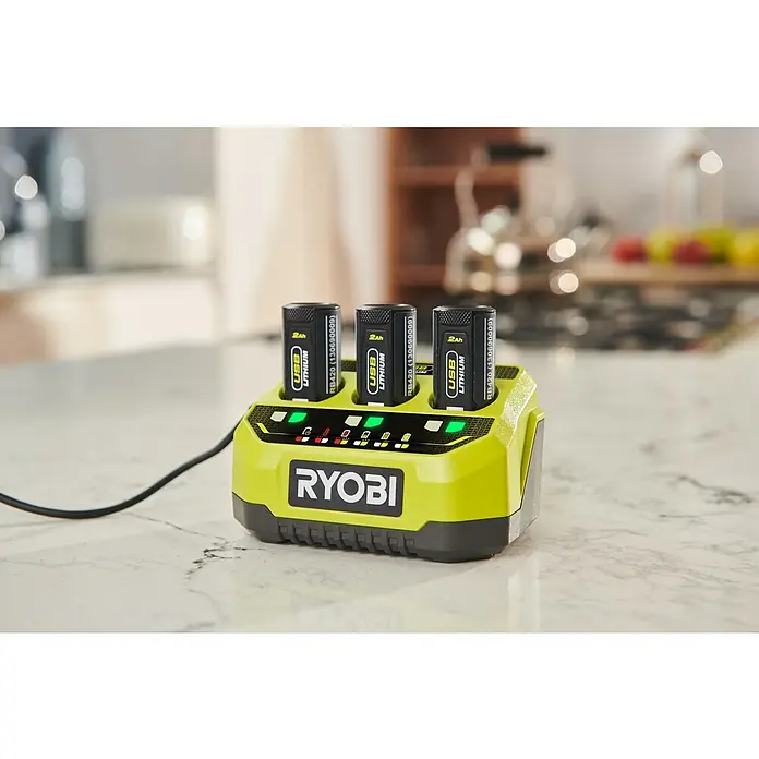 Ryobi 4V USB Schnellladegerät RC43P - Passend für: Ryobi 4V USB-Lithium-Akkus - Nahaufnahme eines Ryobi-Ladegeräts mit drei USB-Lithiumbatterien, die auf einer hellen Arbeitsplatte aufgeladen werden.