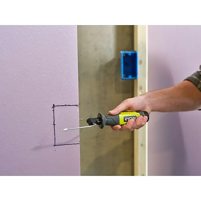 Ryobi 4V USB Akku-Heißdrahtschneider RHC4 - 4 V, 1 Akku, 2 Ah - Ein RYOBI-Werkzeug wird verwendet, um ein Loch in eine lila Wand neben einem blauen Kasten zu schneiden.