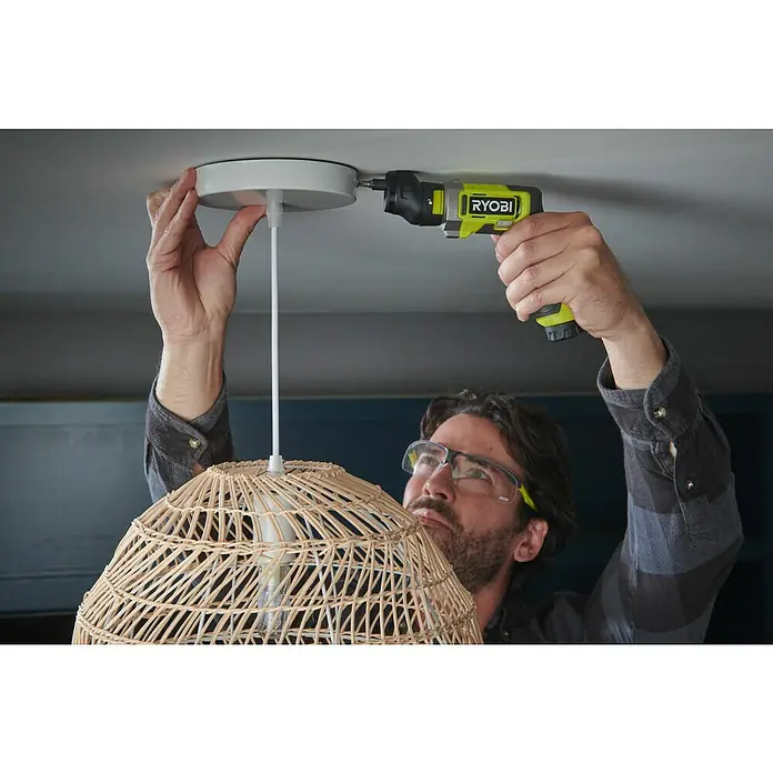 Ryobi 4V USB Akkuschrauber RSD4-120TA2 - 4 V, 1 Akku, 5 Nm - Ein Mann befestigt eine Deckenleuchte mit einem gelben Ryobi Akku-Schraubendreher. Er trägt dabei eine Schutzbrille.