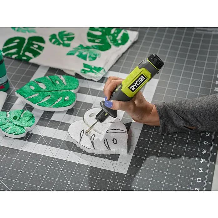 Ryobi 4V USB Akku-Heißdrahtschneider RHC4 - 4 V, 1 Akku, 2 Ah - Nahaufnahme eines RYOBI-Rotationswerkzeugs, das zum Basteln an einem Monstera-Blatt verwendet wird, auf einer grauen Schneidematte.
