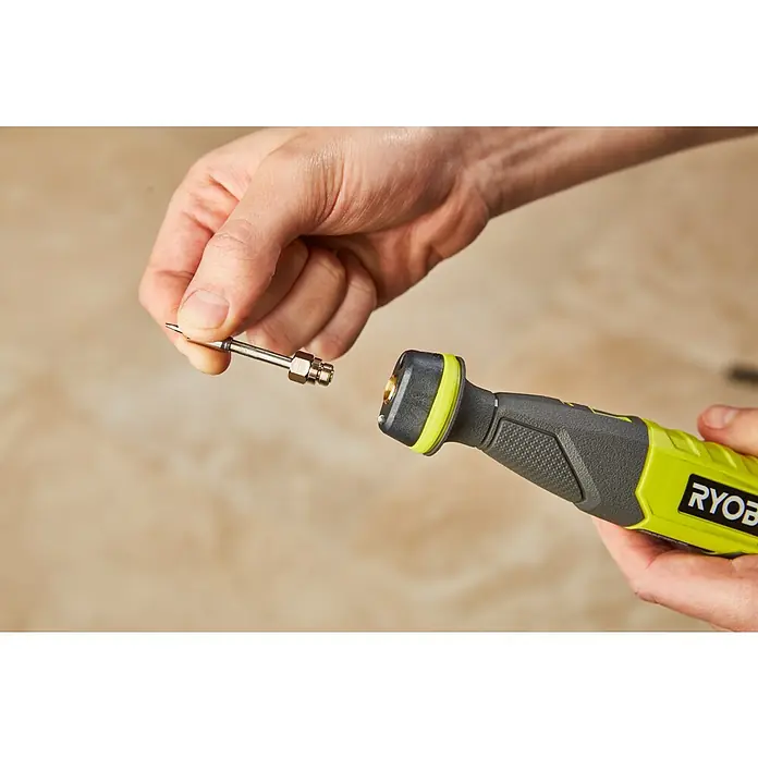 Ryobi 4V USB Akku-Lötstift RSI4-120G - 4 V, 1 Akku, 2 Ah - Nahaufnahme einer Person, die einen Aufsatz an einem Ryobi-Multifunktionswerkzeug befestigt. Das Werkzeug ist gelb und grau, der Aufsatz silberfarben.