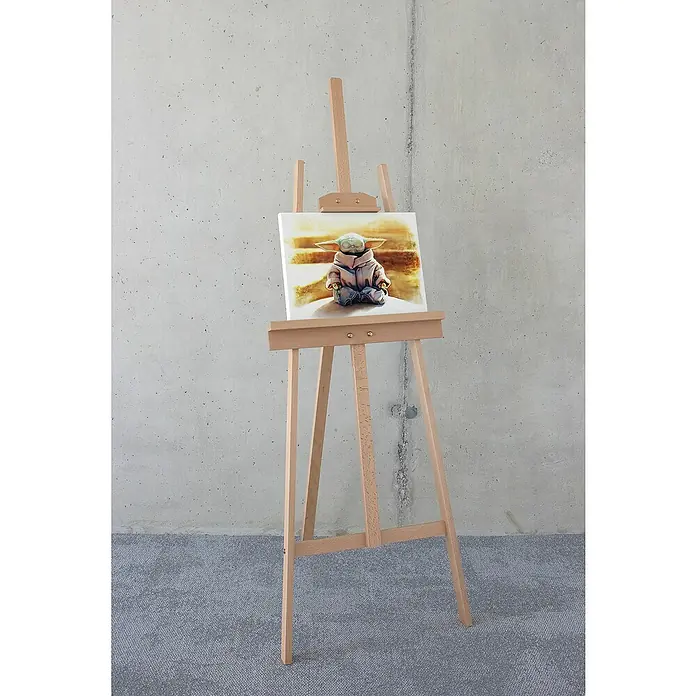 Komar Star Wars Leinwandbild - The Mandalorian - Grogu Meditation King, B x H: 40 x 30 cm - Das Bild zeigt eine bezaubernde „Baby Yoda“-Leinwand auf einer Holzstaffelei, die das Gemälde ins rechte Licht rückt. Die Leinwand ist ein echter Hingucker!