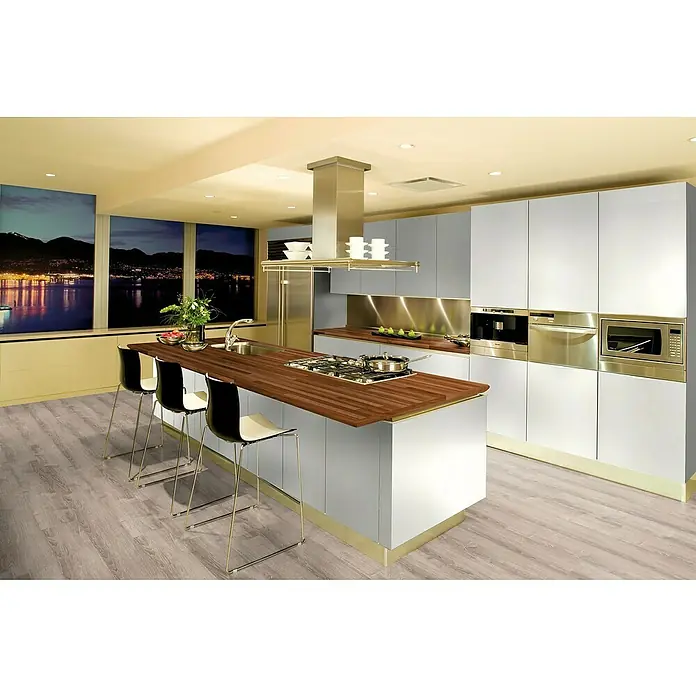 Laminado Roble Cuarzo - 1.380 x 193 x 10 mm, AC5 - Cocina moderna con isla y taburetes bajo una campana extractora, complementada con electrodomésticos integrados y una ventana con vistas a la ciudad.