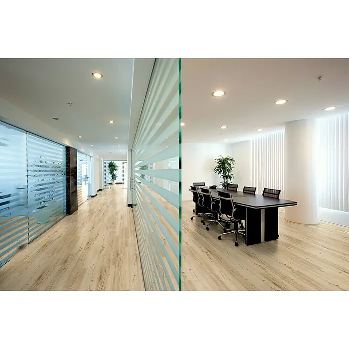 Laminado Roble Serena - 1.380 x 193 x 12 mm, AC5 - Interior de oficina con mesa de conferencias y suelo de madera. El espacio es luminoso y moderno con paredes de vidrio.