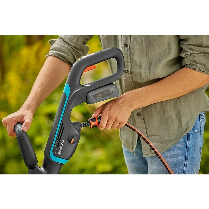 Gardena Power for All 18V Akku-Reinigungsbürste AquaBrush Patio 03/18V - 1 Akku - Nahaufnahme einer GARDENA Akku-Bürste zum Reinigen von Oberflächen im Außenbereich, die an einen Gartenschlauch angeschlossen ist.