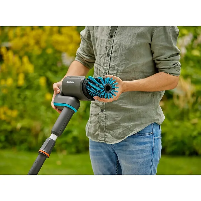 Gardena Power for All 18V Akku-Reinigungsbürste AquaBrush Patio 03/18V - 1 Akku - Der Gardena Bürstenroller wird von einer Person gehalten. Er verfügt über blaue Borsten für die Reinigung und Pflege im Außenbereich.
